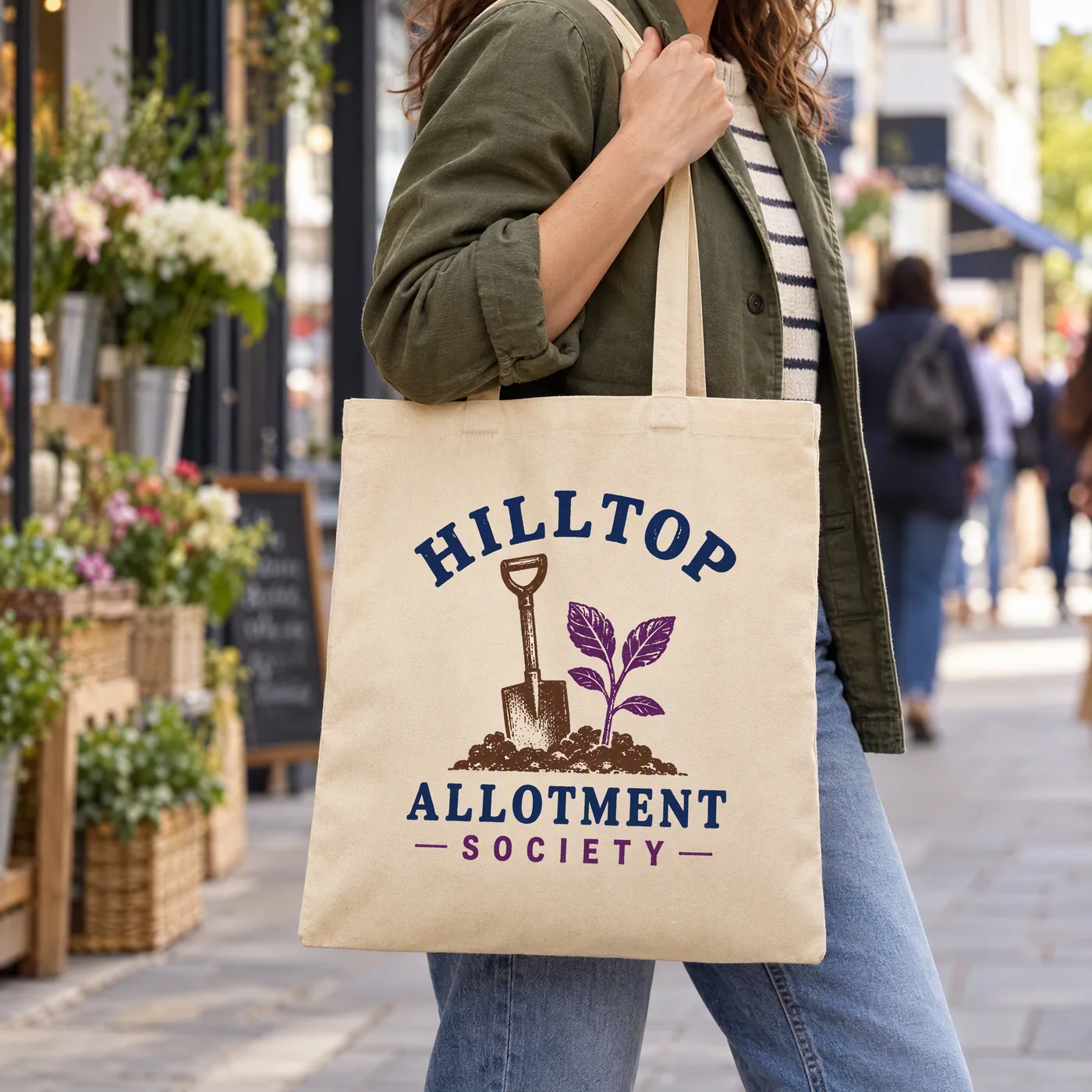 Natural recycled canvas shopper printed with a Hilltop Allotment Society logo, carried over the shoulder on a street